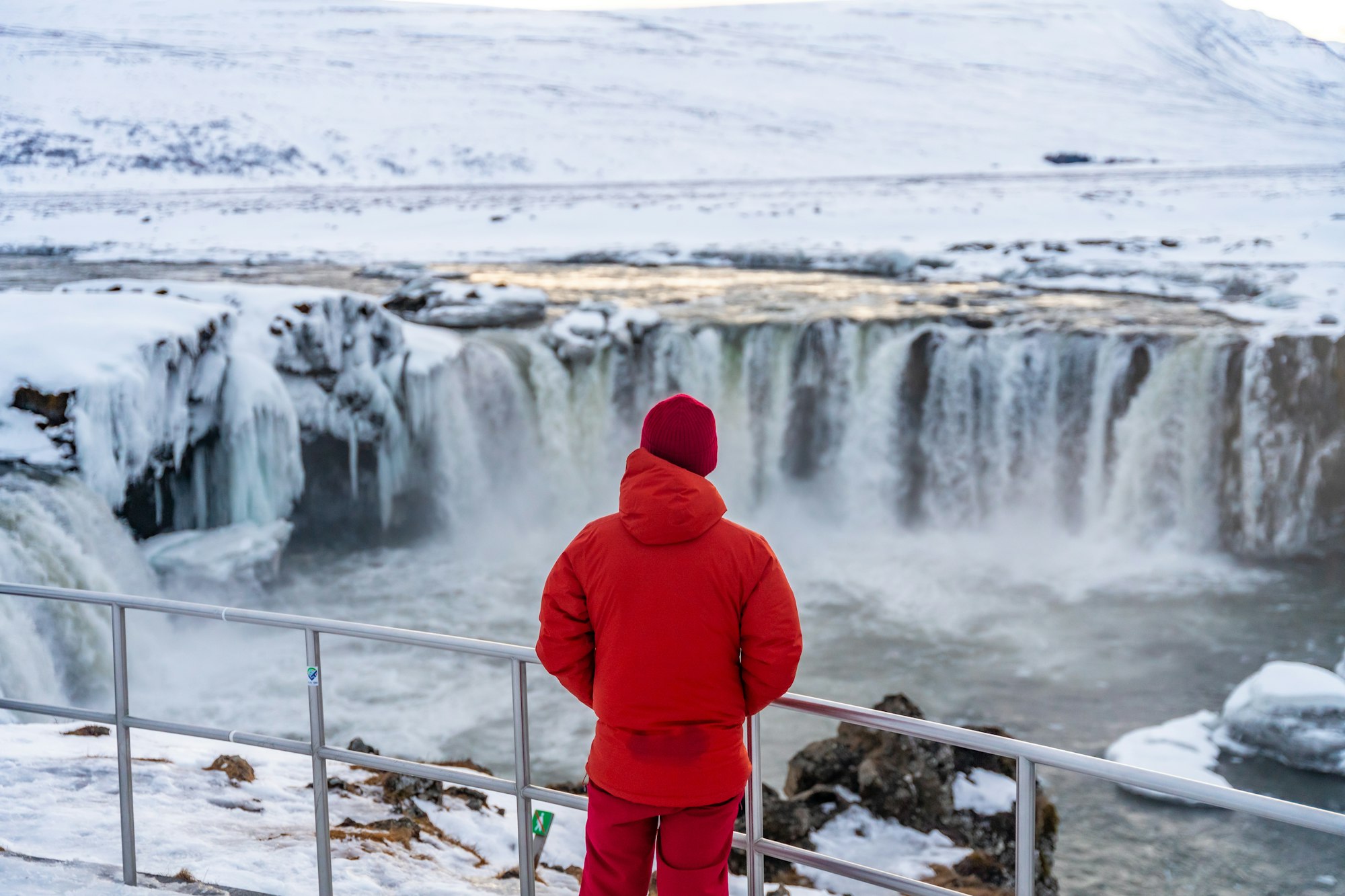 Man with his back turned at the beautiful Godafoss waterfall winter in Iceland